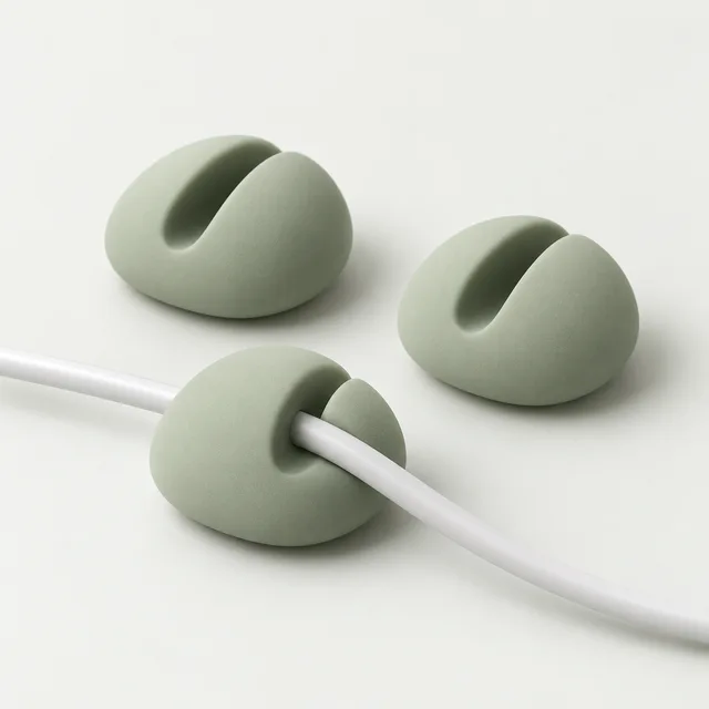 Concept render of three sage green pebble cable clips with a white cable